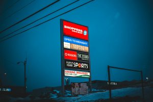 Illuminated big board with signs of shops and stores under dark sky in winter season