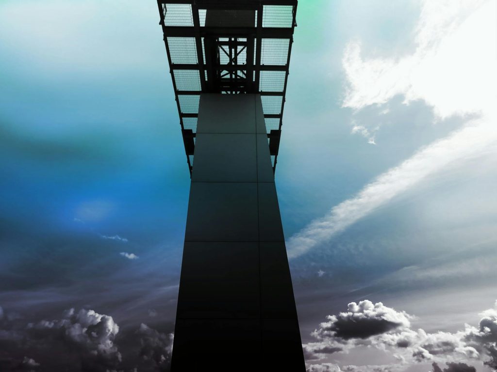A striking view of a steel structure reaching into a vibrant, cloudy sky, showcasing modern architecture.