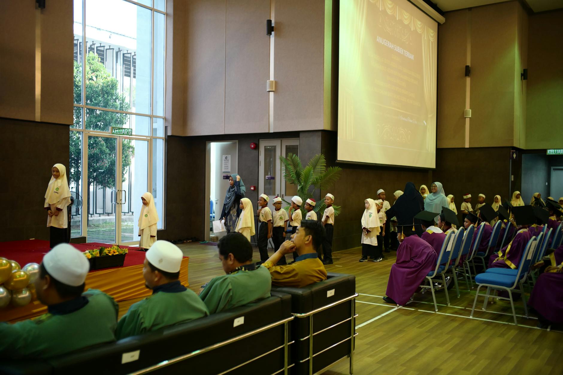 Young students in traditional attire at a school graduation ceremony in Shah Alam, Malaysia.