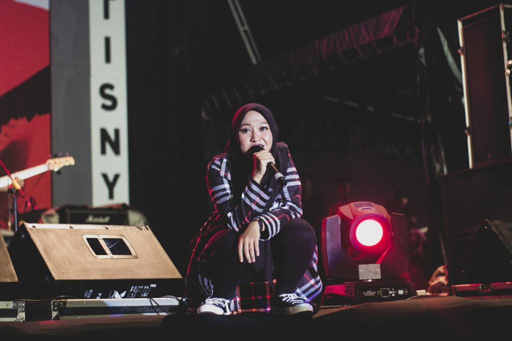 A female singer in a hijab performing on stage during a night concert in Sibolga, Indonesia.