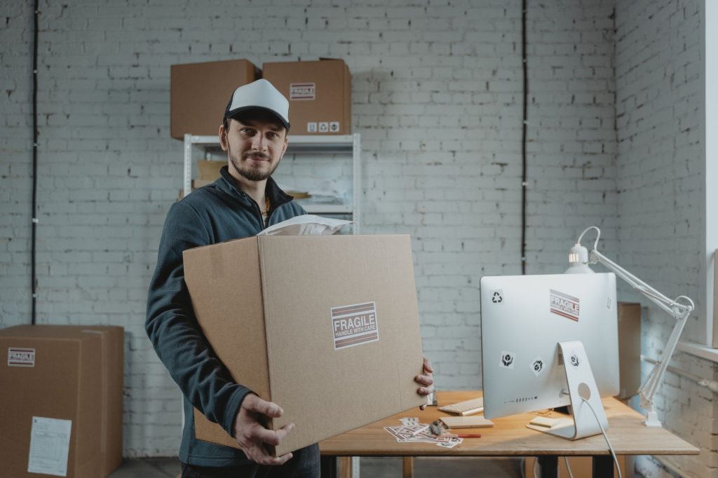 Courier holding a large cardboard box in a modern office. Professional delivery service indoors.