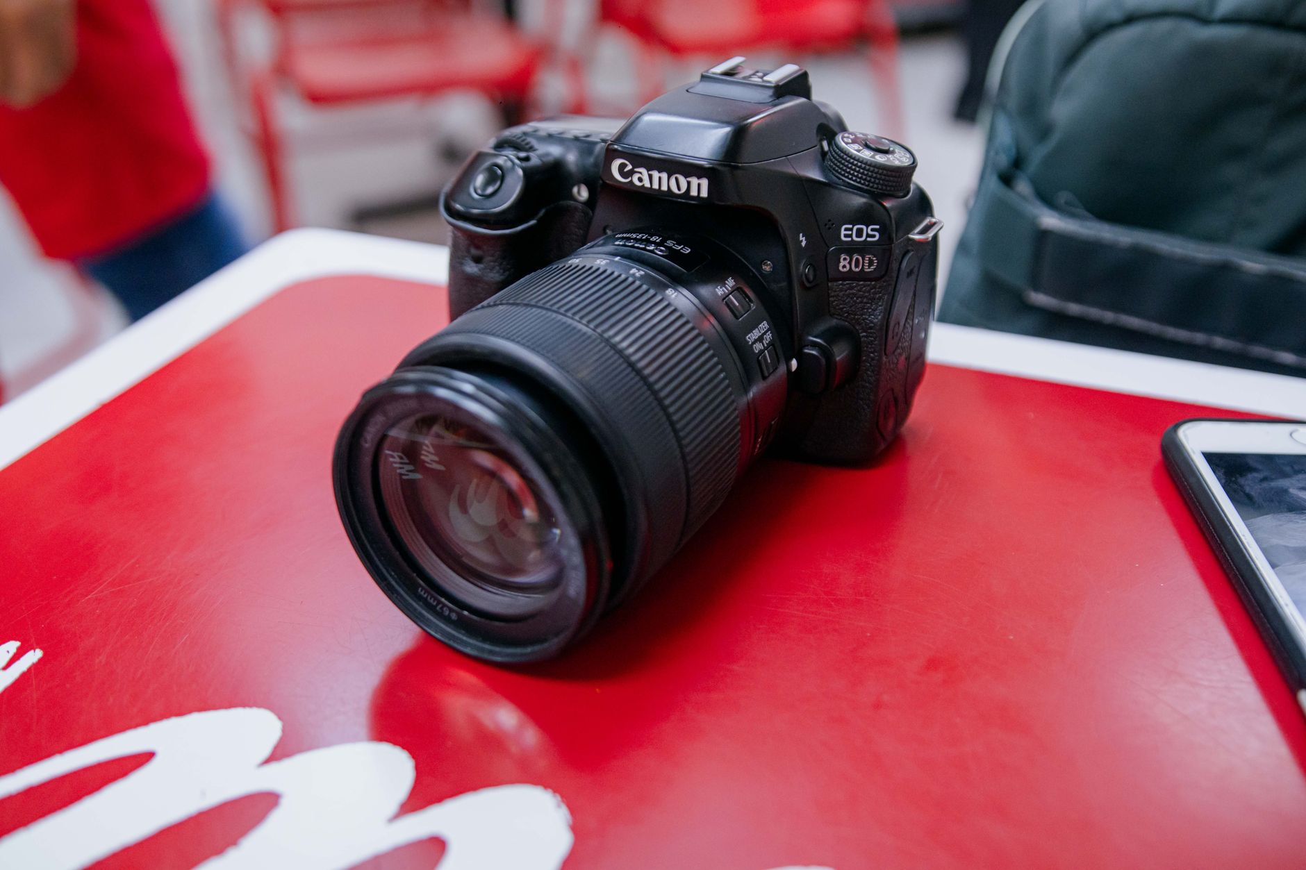Close-up of a black DSLR camera resting on a vibrant red table surface.