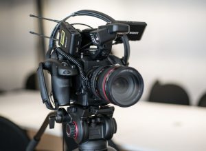 Close-up of a professional video camera setup on a tripod for videography use in a studio setting.