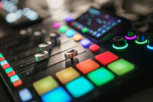 Close-up of a vibrant audio mixing console with colorful illuminated buttons and sliders.
