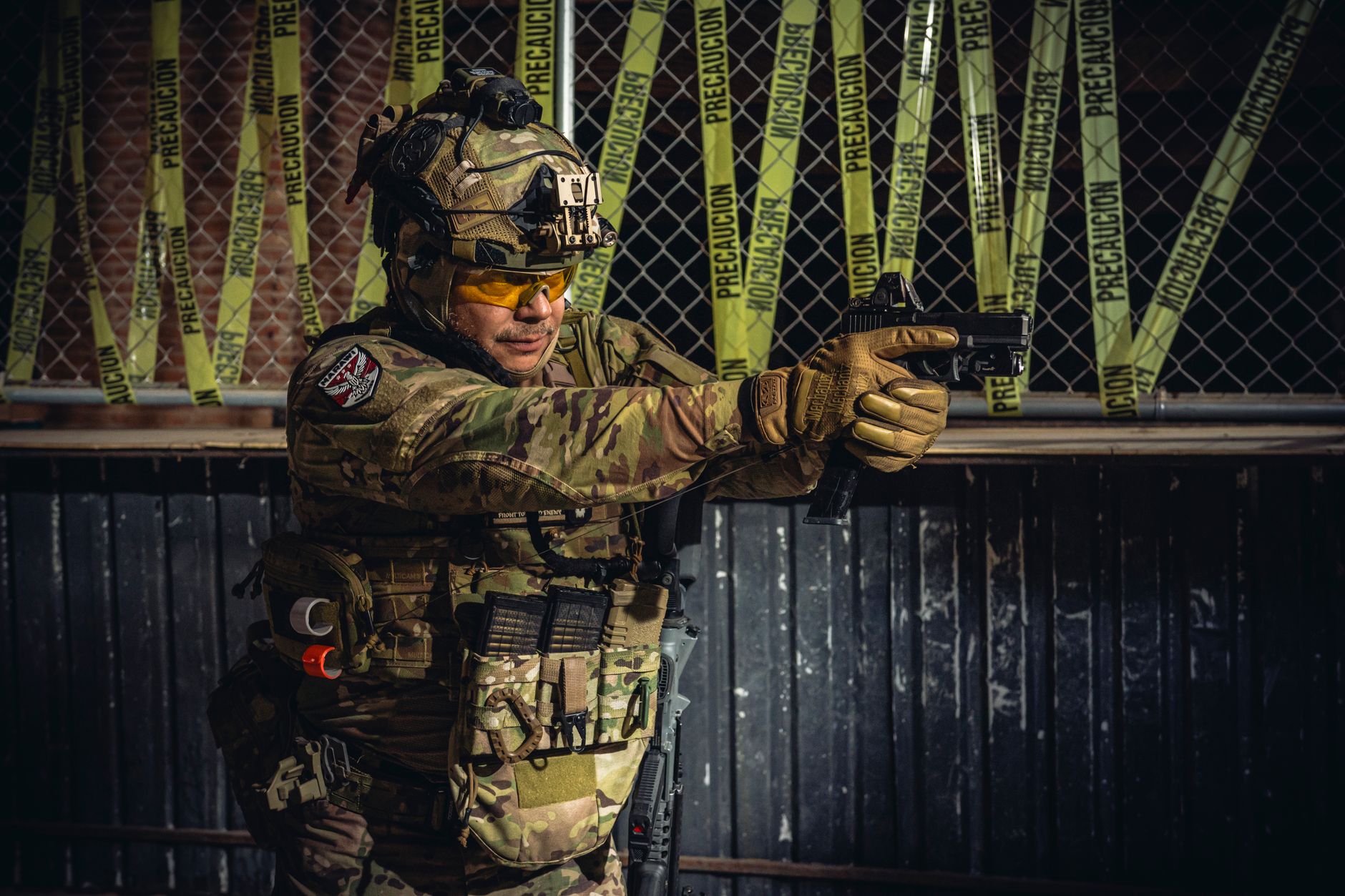 Tactical soldier in camo gear with weapon training indoors with caution tape background.