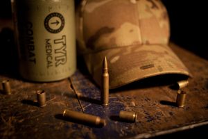 Camouflage cap and combat ammunition on rustic surface.