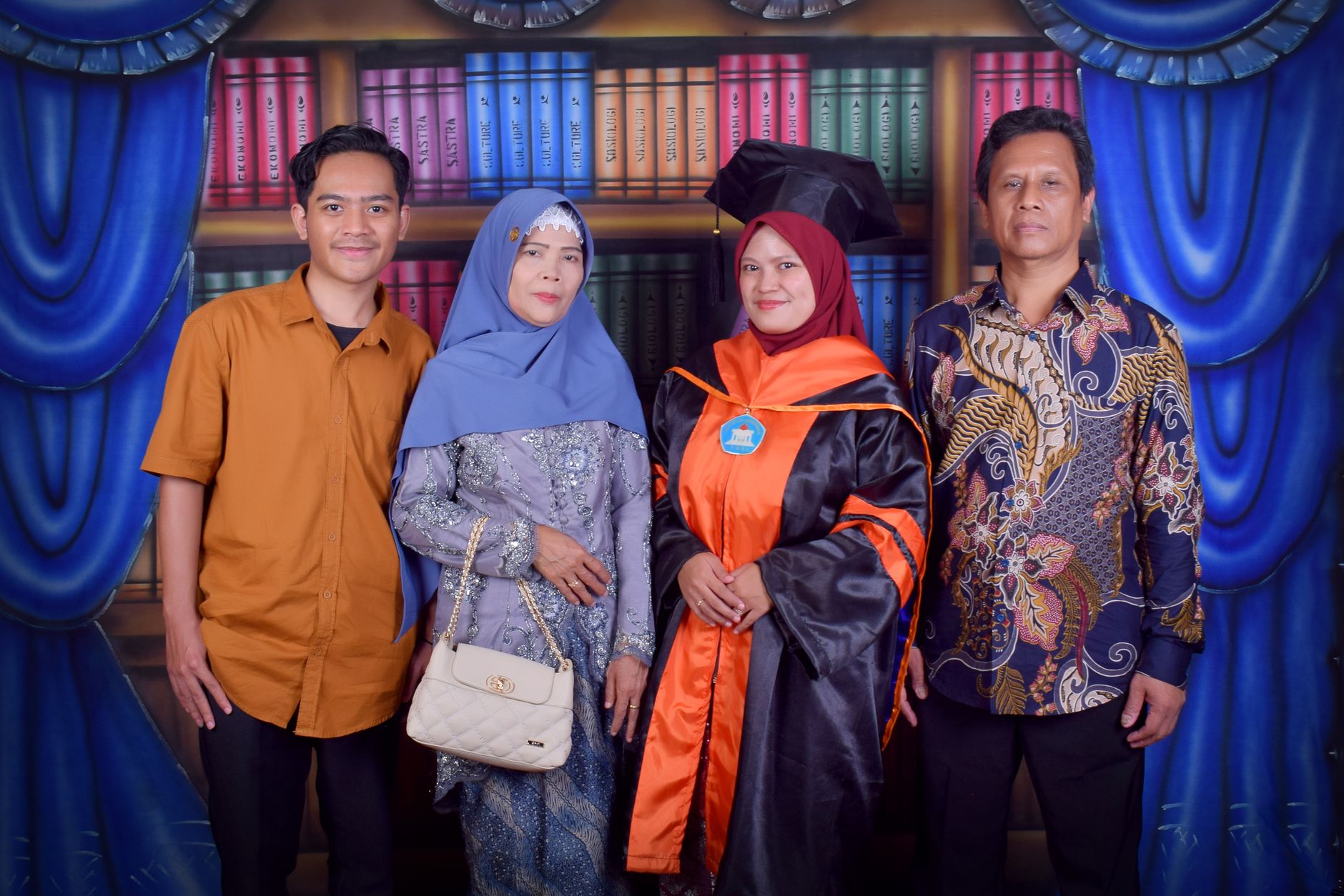 Family posing together for a graduation photo with a backdrop of bookshelves.