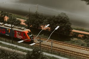 A vibrant train travels along the railway in São Paulo, surrounded by greenery and street lights.
