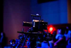 A high-quality camera setup capturing a live studio event with an audience in the background.