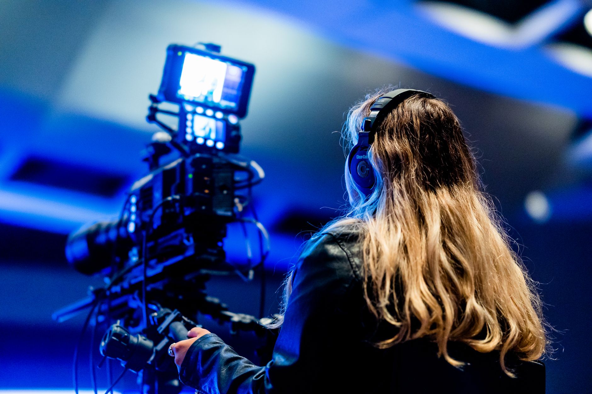 A cameraperson using professional equipment indoors for filming. High-tech setup.
