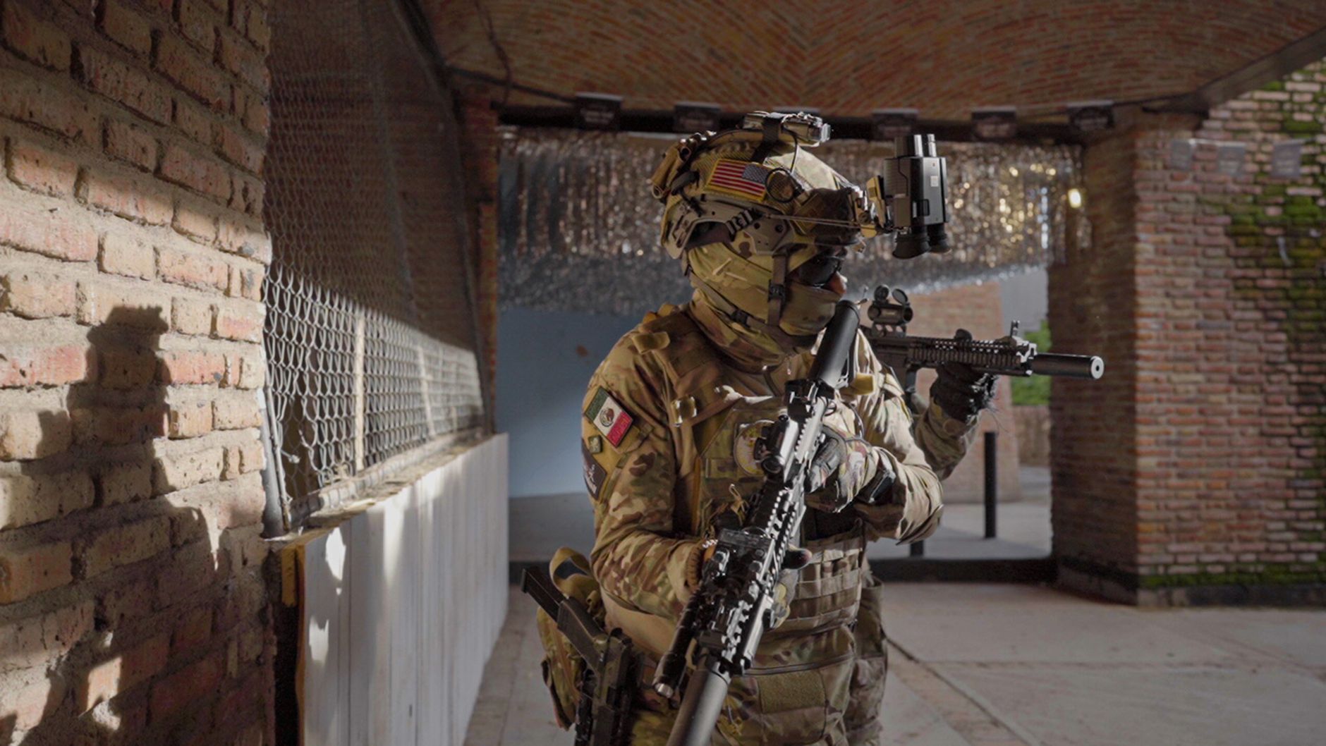 A soldier in tactical gear with firearms in an urban environment, showcasing military readiness.