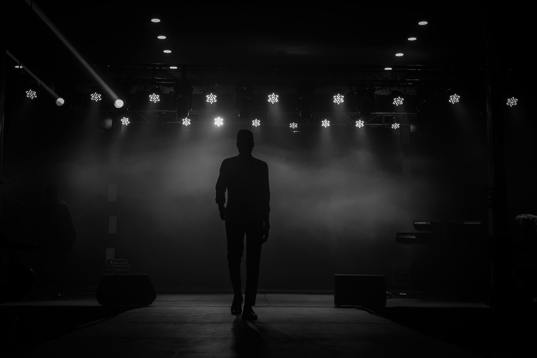 A lone performer in silhouette, walking on stage under dramatic lights in Ibadan, Nigeria.