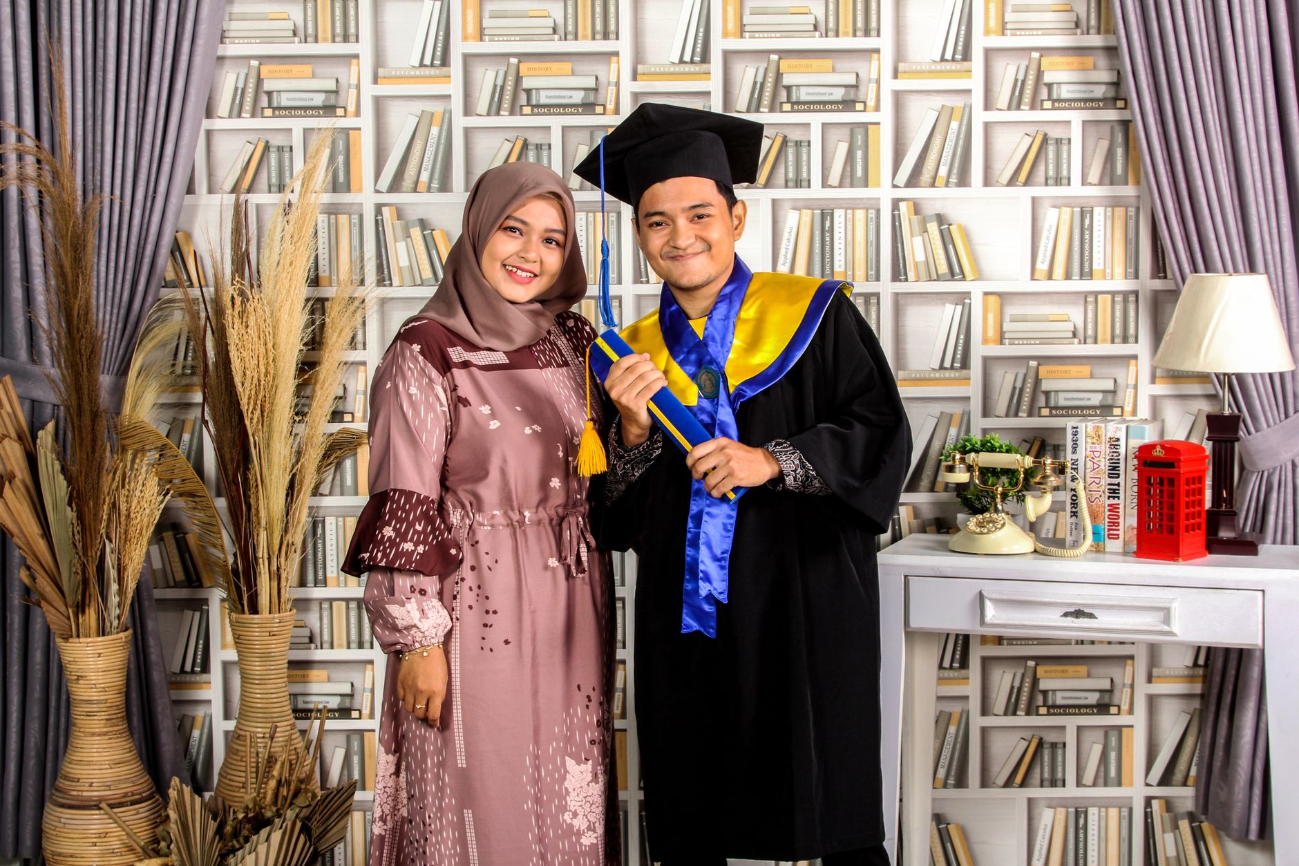 Two graduates in traditional attire celebrate their achievement with smiles.